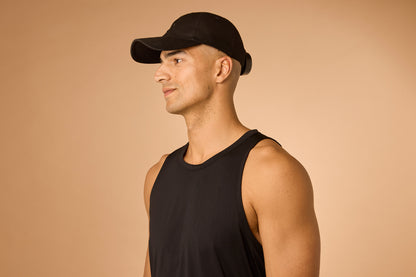 Man wearing a black cap and tank top on a beige background
